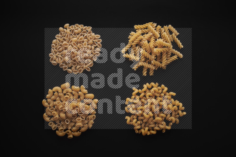 Different pasta types in bunches on black background