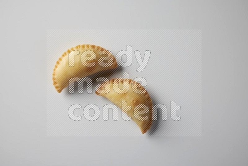 Two fried sambosa from a top angle on a white background