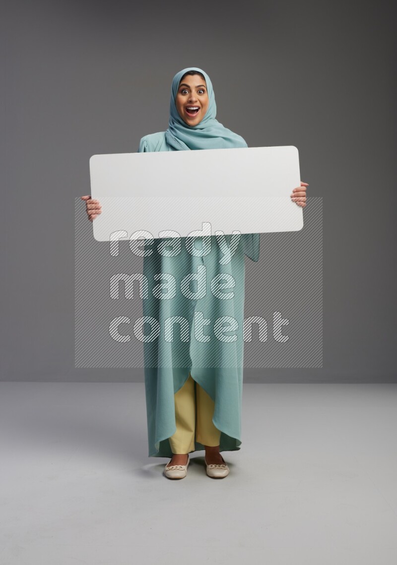 Saudi Woman wearing Abaya standing holding board on Gray background