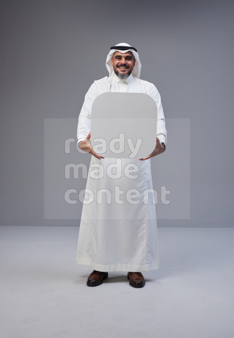 Saudi man Wearing Thob and white Shomag standing holding social media sign on Gray background