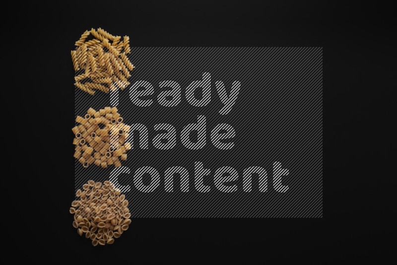 Different pasta types in 3 bunches on black background