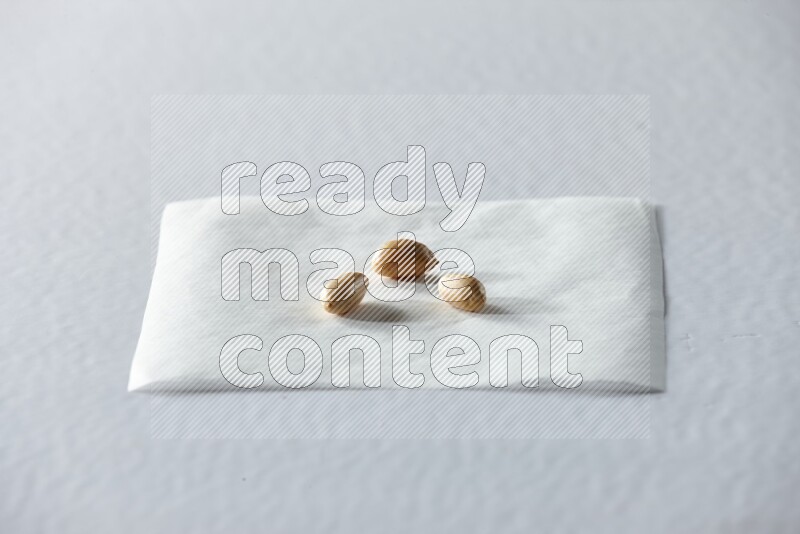 3 peeled peanuts on a piece of paper on a white background in different angles