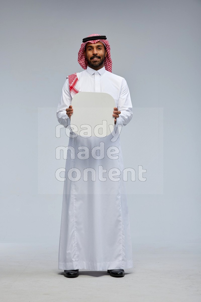 Saudi man Wearing Thob and shomag standing holding social media sign on Gray background