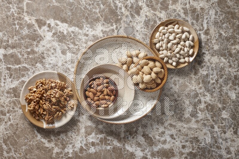 Nuts in pottery plates and wooden bowls in a light setup