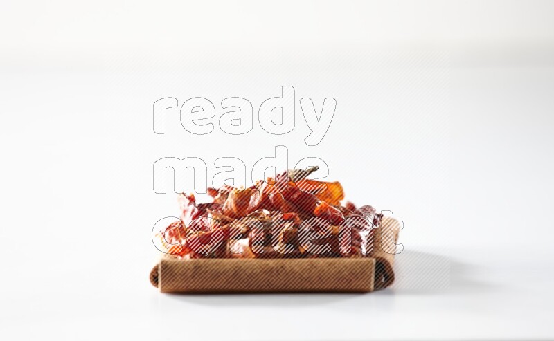 أربعة من أعواد القرفة مكونة شكل مربع بداخلها فلفل حار علي خلفية بيضاء