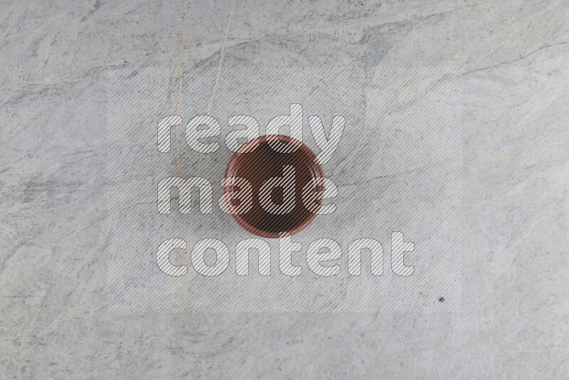 A brown pottery bowl on grey marble background