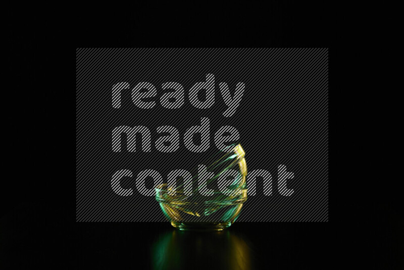 Glassware with rim light in green and yellow against black background