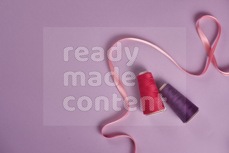 A pink and purple collection of sewing and tailoring tools arranged on a purple background