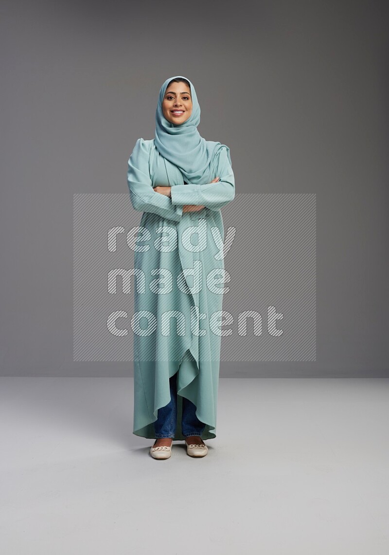 Saudi Woman wearing Abaya standing with crossed arms on Gray background