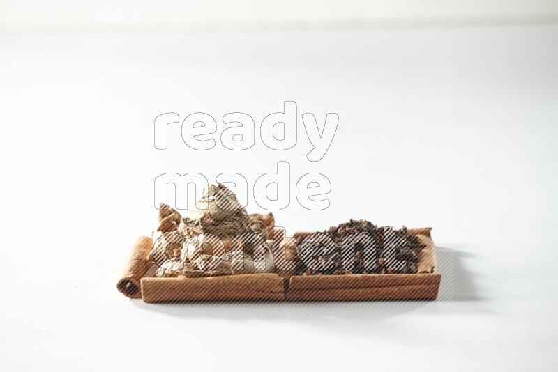 مربعان من أعواد القرفة ممتلئان بالقرنفل والزنجبيل المجفف علي خلفية بيضاء