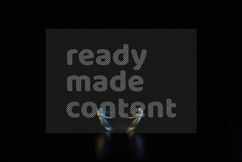 Glassware with rim light in blue and yellow against black background