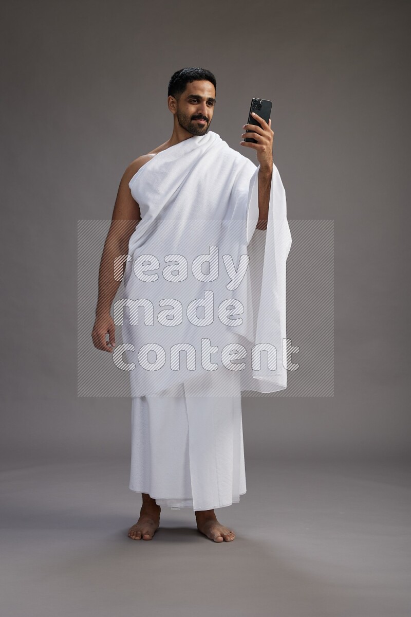 A man wearing Ehram Standing taking selfie on gray background