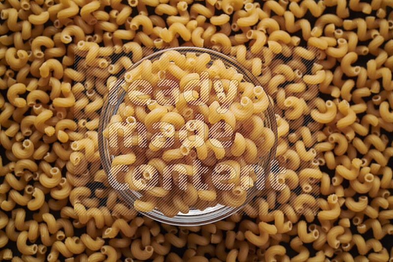 Twist pasta in a glass bowl on black background