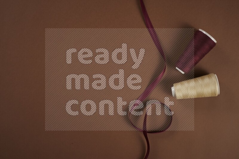 A red collection of sewing and tailoring tools arranged on a brown background