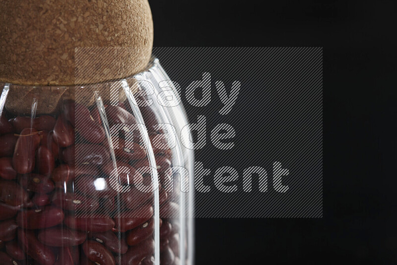 Red kidney beans in a glass jar on black background