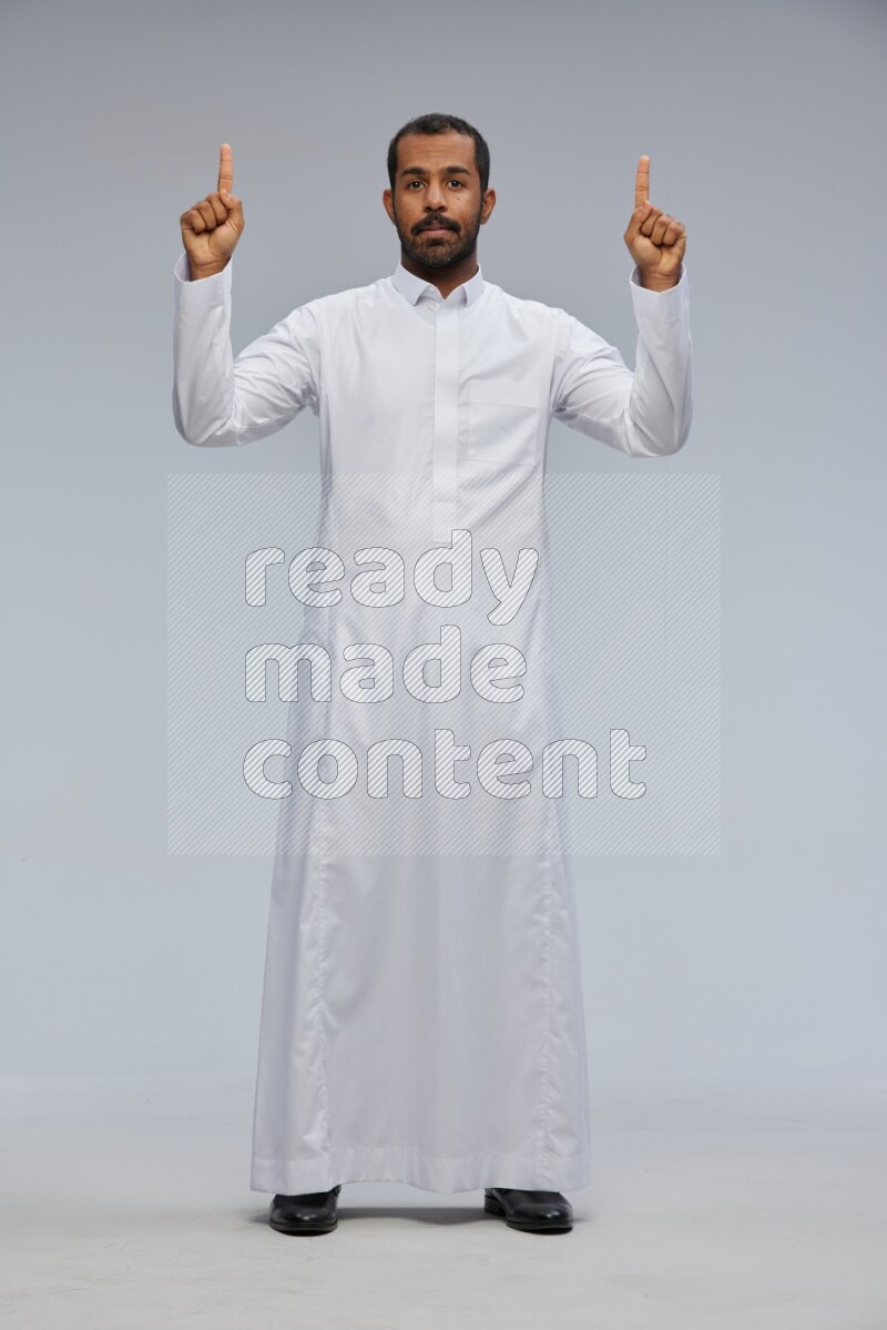 Saudi man Wearing Thob standing interacting with the camera on Gray background