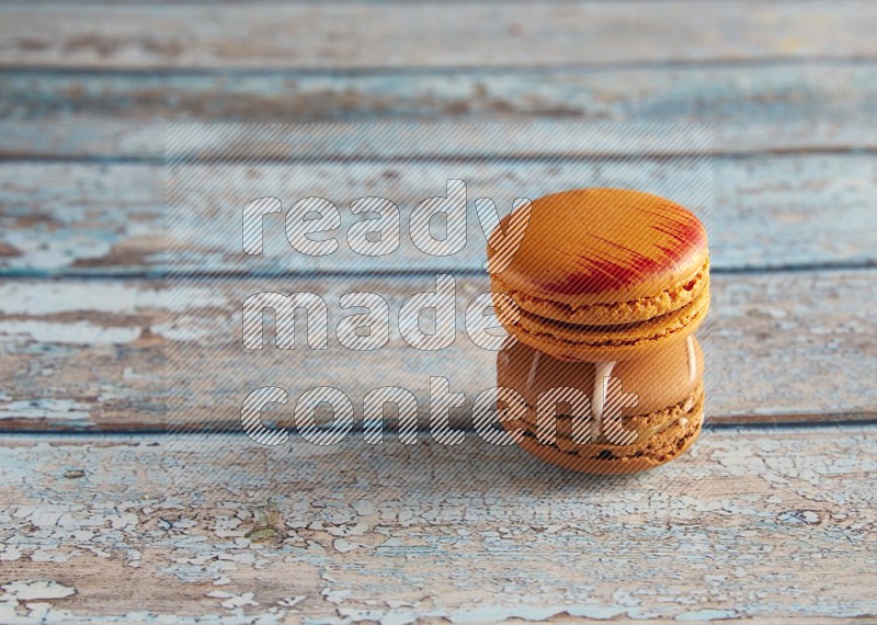 45º Shot of of two assorted Brown Irish Cream, and Orange Exotic macarons on light blue background