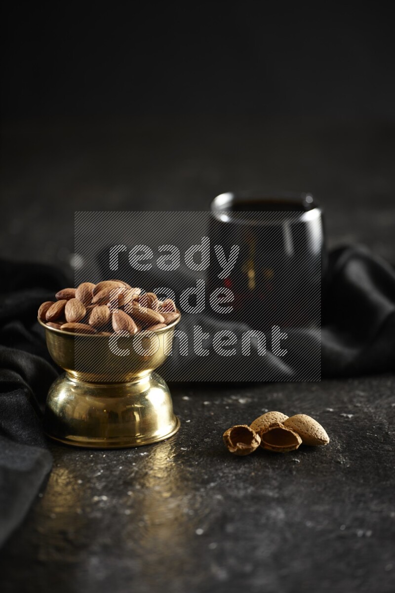 Nuts in a metal bowl with tamarind and a napkin in a dark setup