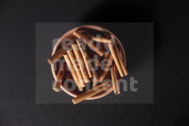 Cinnamon Sticks in a wooden bowl on black background