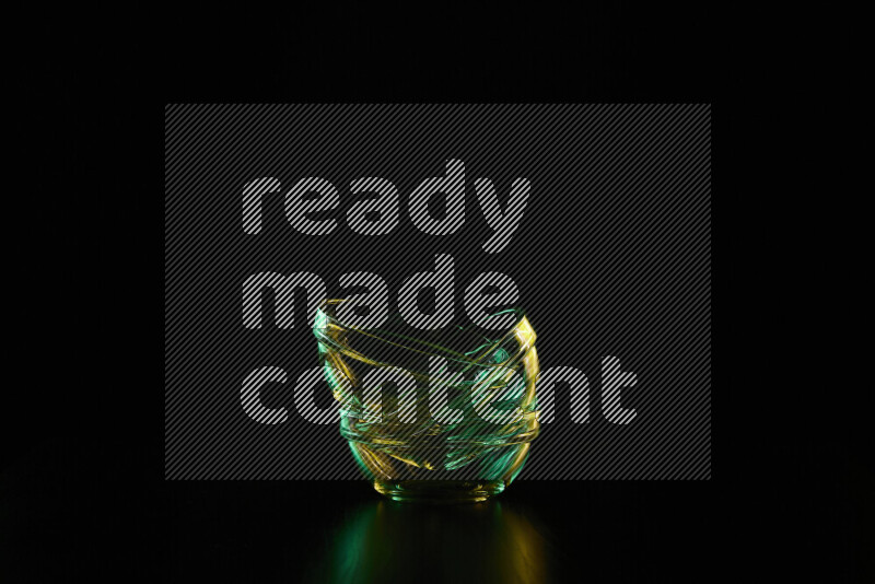 Glassware with rim light in green and yellow against black background