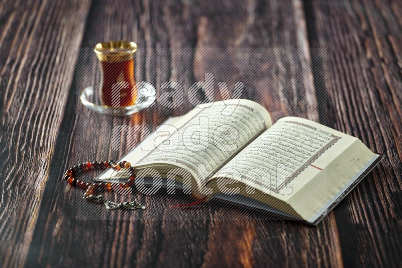 Quran with dates, prayer beads and different drinks all placed on wooden background