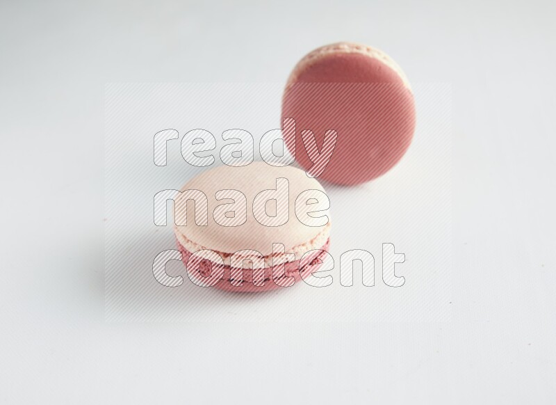 45º Shot of two Pink Litchi Raspberry macarons on white background