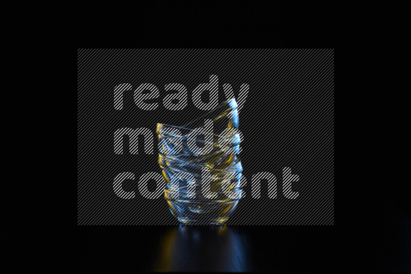 Glassware with rim light in blue and yellow against black background