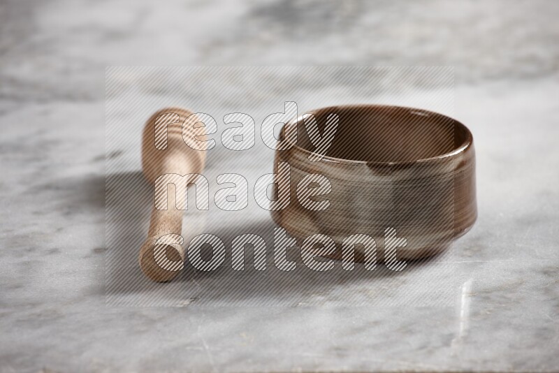 Multicolored pottery bowl with wooden honey dipper on the side on grey marble background