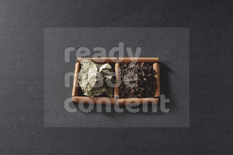 2 squares of cinnamon sticks full of cloves and bay laurel leaves on black flooring