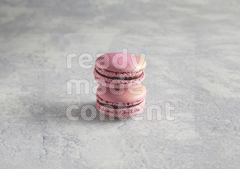 45º Shot of two Purple Strawberry macarons on white  marble background