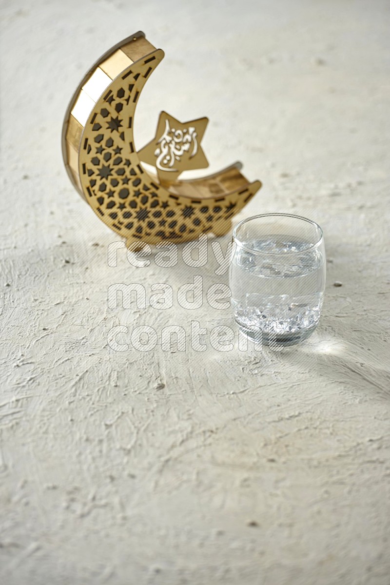 A crescent lantern with drinks, dates, nuts, prayer beads and quran on textured white background