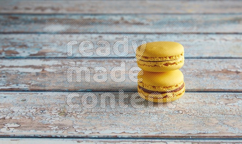 45º Shot of two Yellow Lemon macarons on light blue wooden background