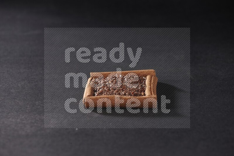 أربعة من أعواد القرفة مكونة شكل مربع بداخلها بذور الكتان علي خلفية سوداء