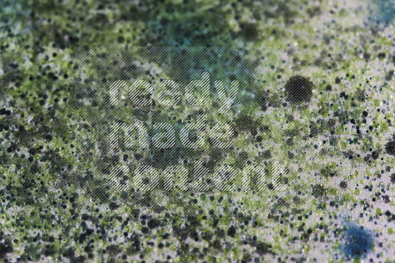 لقطات مقربة لقطرات ألوان مائية خضراء وزرقاء على سطح الزيت على خلفية بيضاء