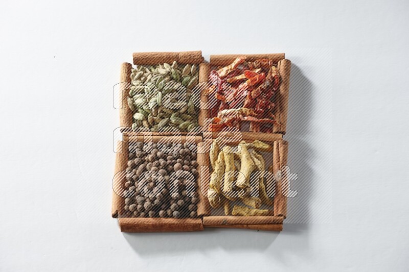 4 squares of cinnamon sticks full of dried red chilis, cardamom, turmeric fingers and allspice on white flooring
