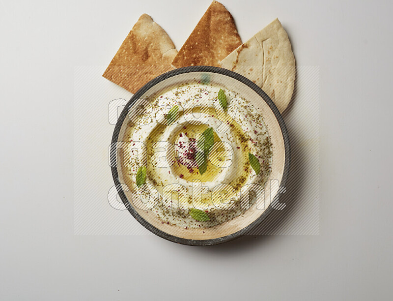 Lebnah garnished with zaater, mint & sumak in a pottery plate on a white background