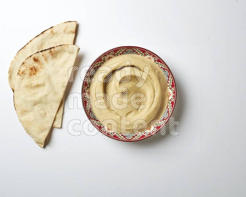 Plain Hummus in a red plate with patterns on a white background
