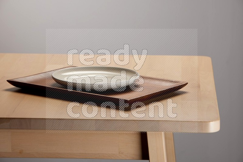 white plate on a rectangular wooden tray on the edge of wooden table