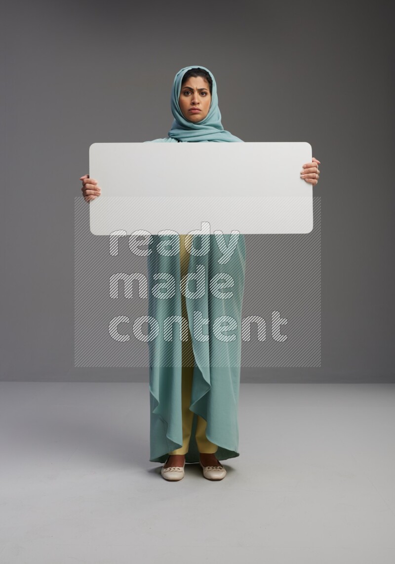 Saudi Woman wearing Abaya standing holding board on Gray background