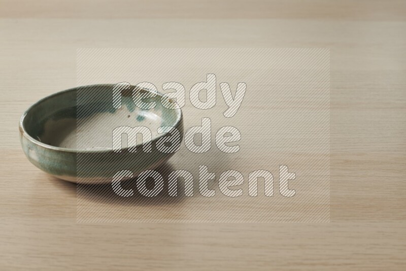 A multicolored pottery bowl on light wooden background