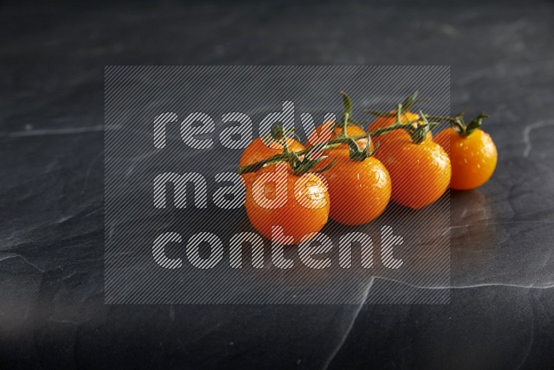 Orange cherry tomato vein on a textured black slate background 45 degree