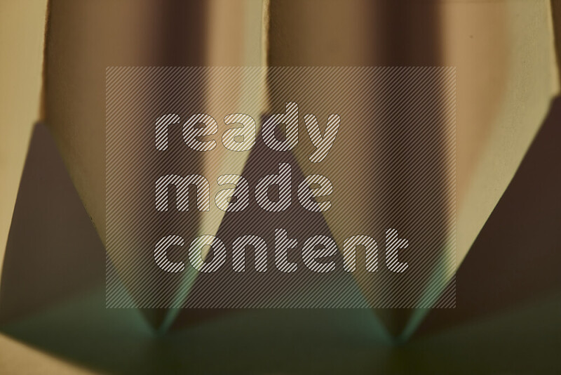 صورة مجردة مقربة تظهر طيات ورقية هندسية حادة بتدرجات اللون الأخضر مع درجات لونية دافئة