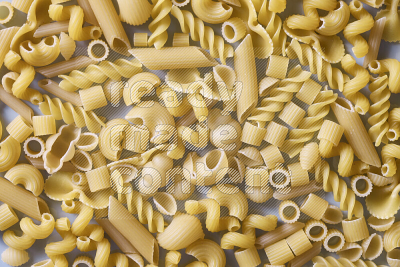 Different pasta types on light blue background