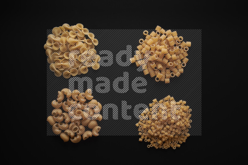 Different pasta types in bunches on black background