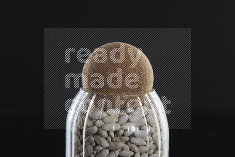 White beans in a glass jar on black background