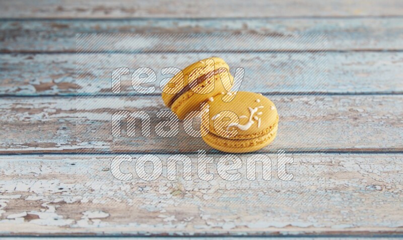 45º Shot of two Yellow Piña Colada macarons on light blue wooden background
