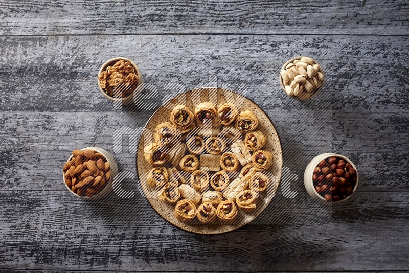 حلويات شرقية في صحن فخاري مع المكسرات والقهوة والعسل علي خلفية خشبية