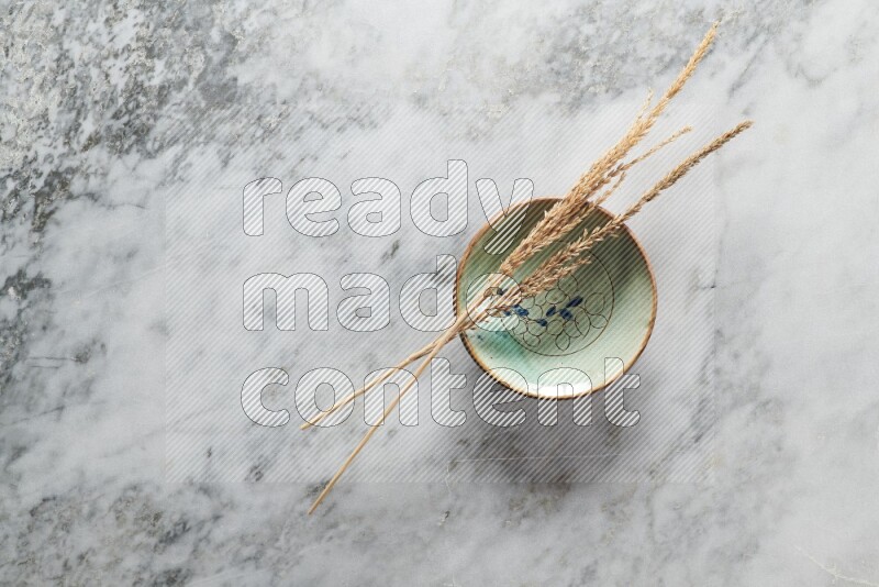 Wheat stalks on decorative pottery plate on grey marble background