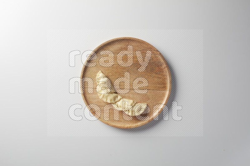 Four Sambosas on a wooden round plate on a white background