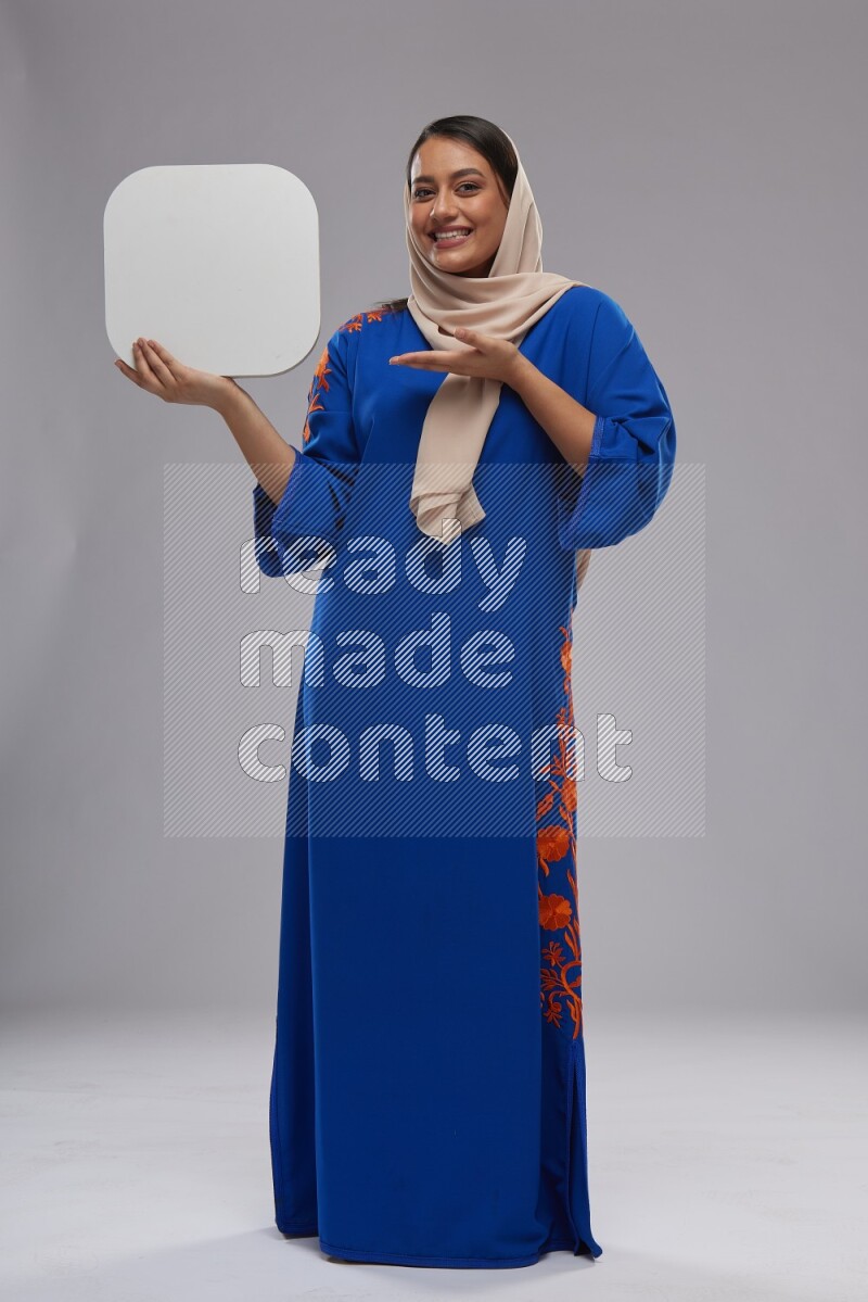 A Saudi woman standing wearing Jalabeya holding a social media sign